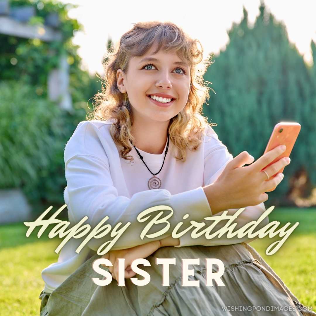 Smiling teenage blonde curly female with a smartphone in her hands, looking at a camera sitting on t